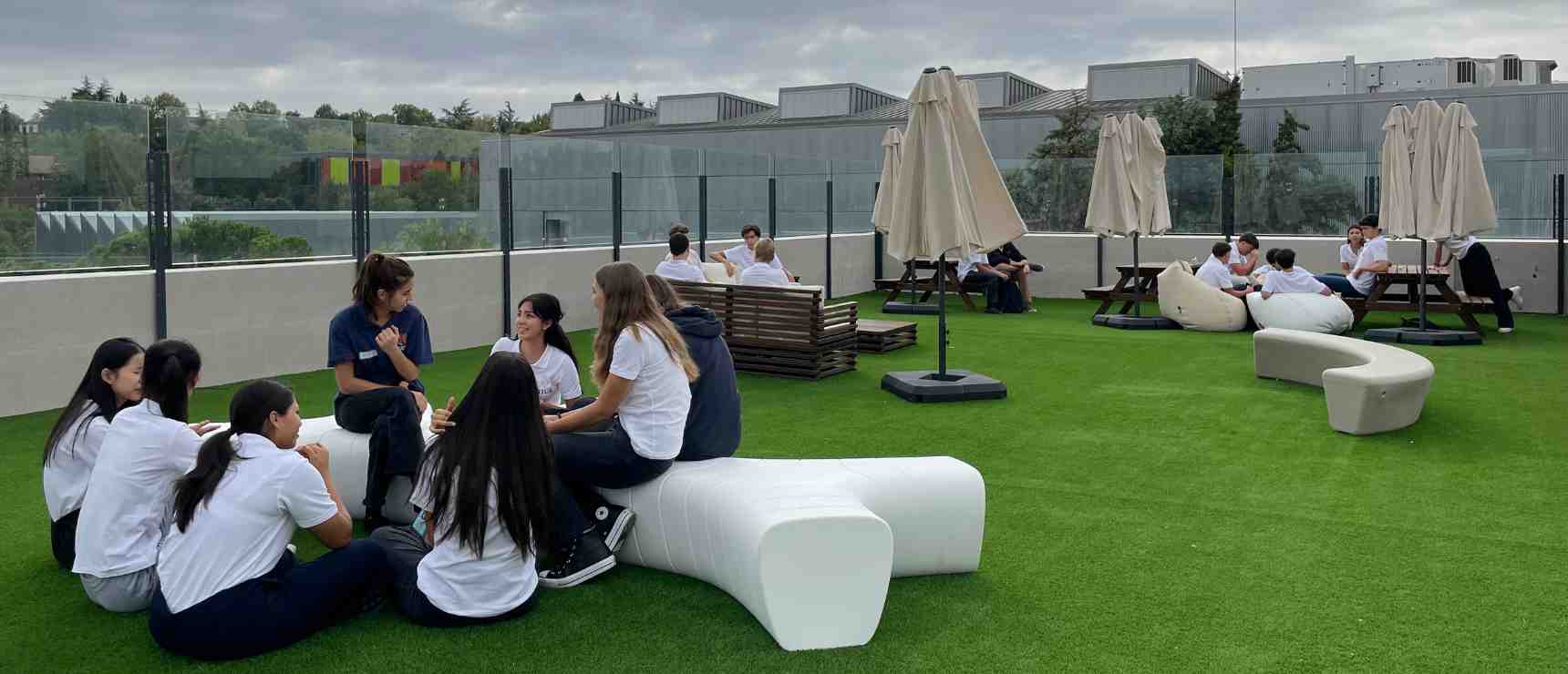 Students relaxing and socializing on a university rooftop garden for outdoor learning and recreation.
