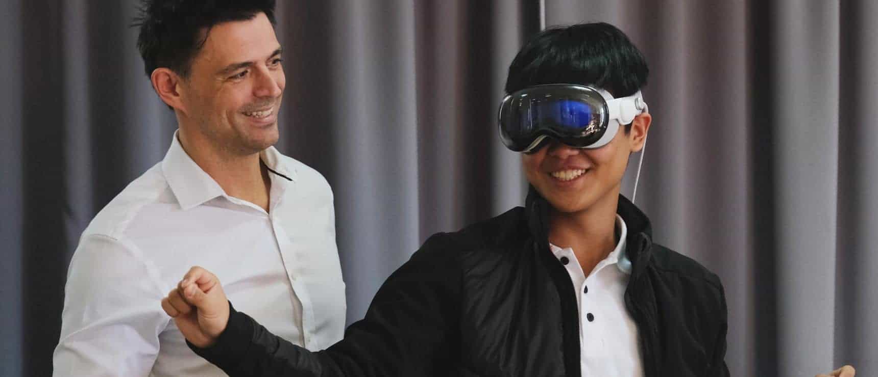 Boy using virtual reality headset with teacher in classroom environment, promoting innovative education at world schools.