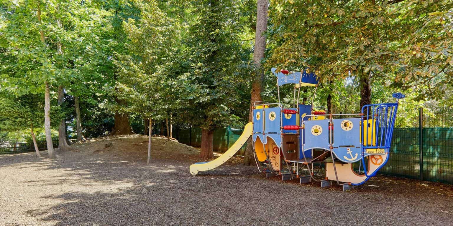 Colorful pirate ship playground set in a shaded outdoor area with trees for children’s play and outdoor learning.