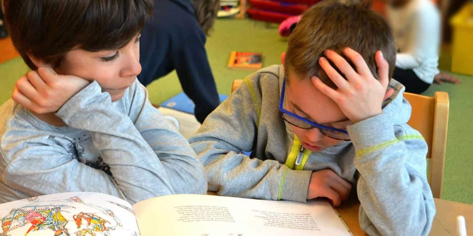 Young students focused on a book in a classroom, highlighting the importance of quality education at World Schools.