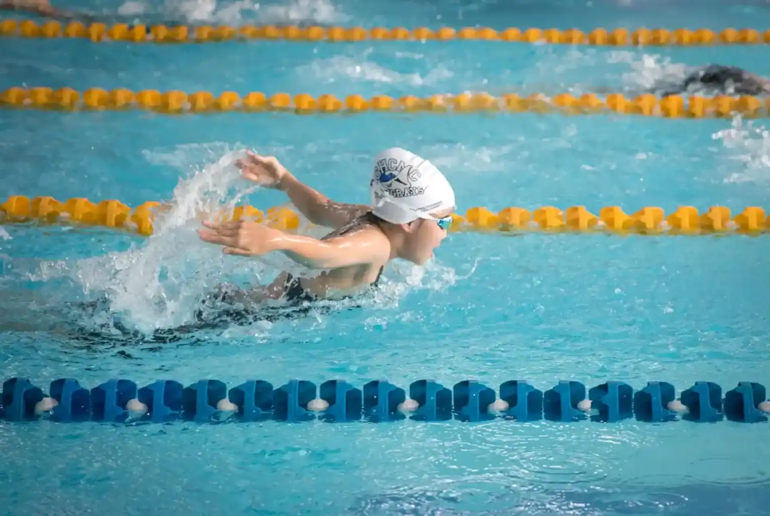 Child swimmer competing in a swimming race at a school sports event.