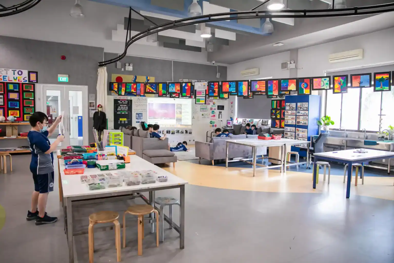 Bright, modern classroom with colorful student artwork, collaborative learning spaces, and educational material displays.