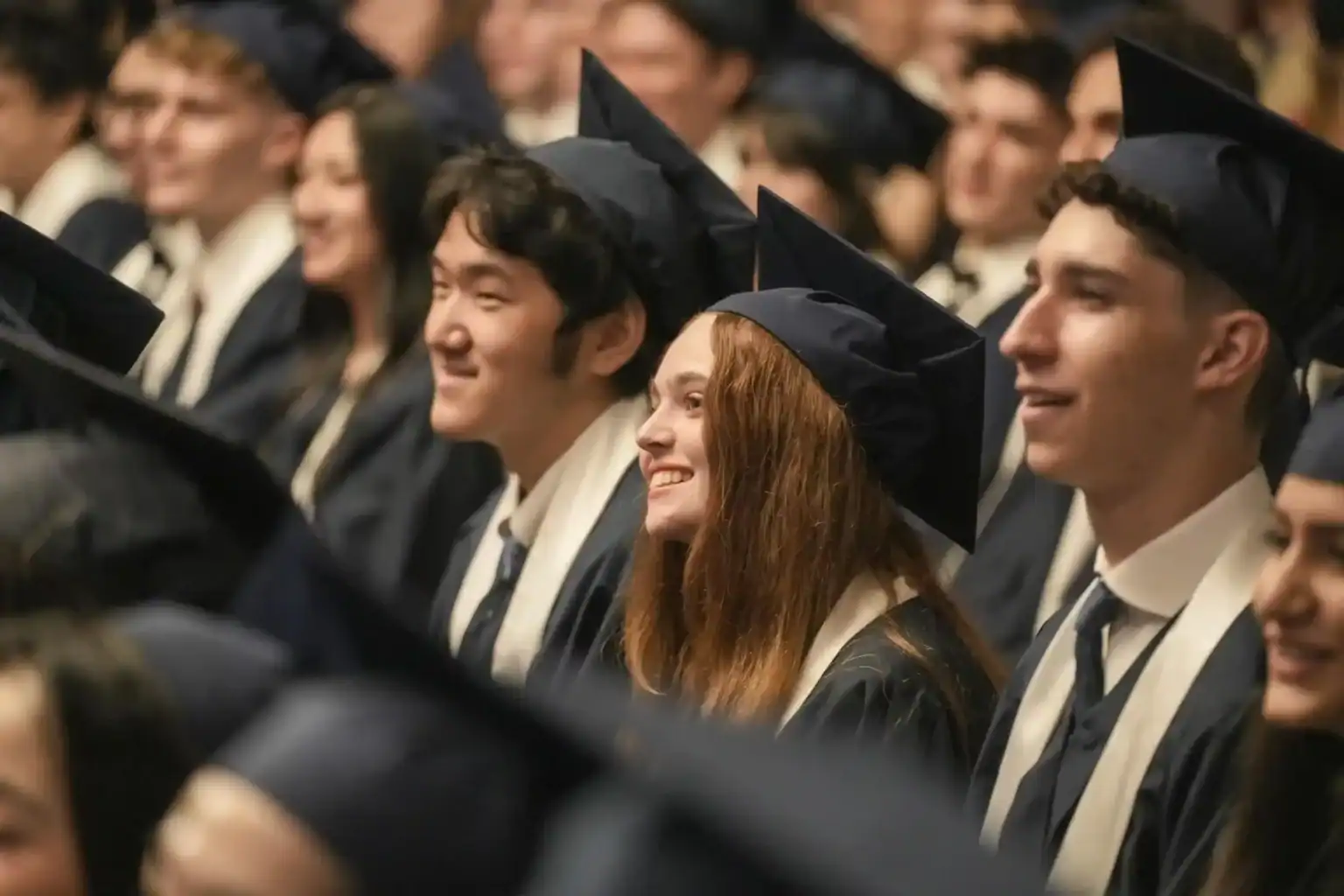 Graduates in caps and gowns celebrating at a world schools graduation ceremony.