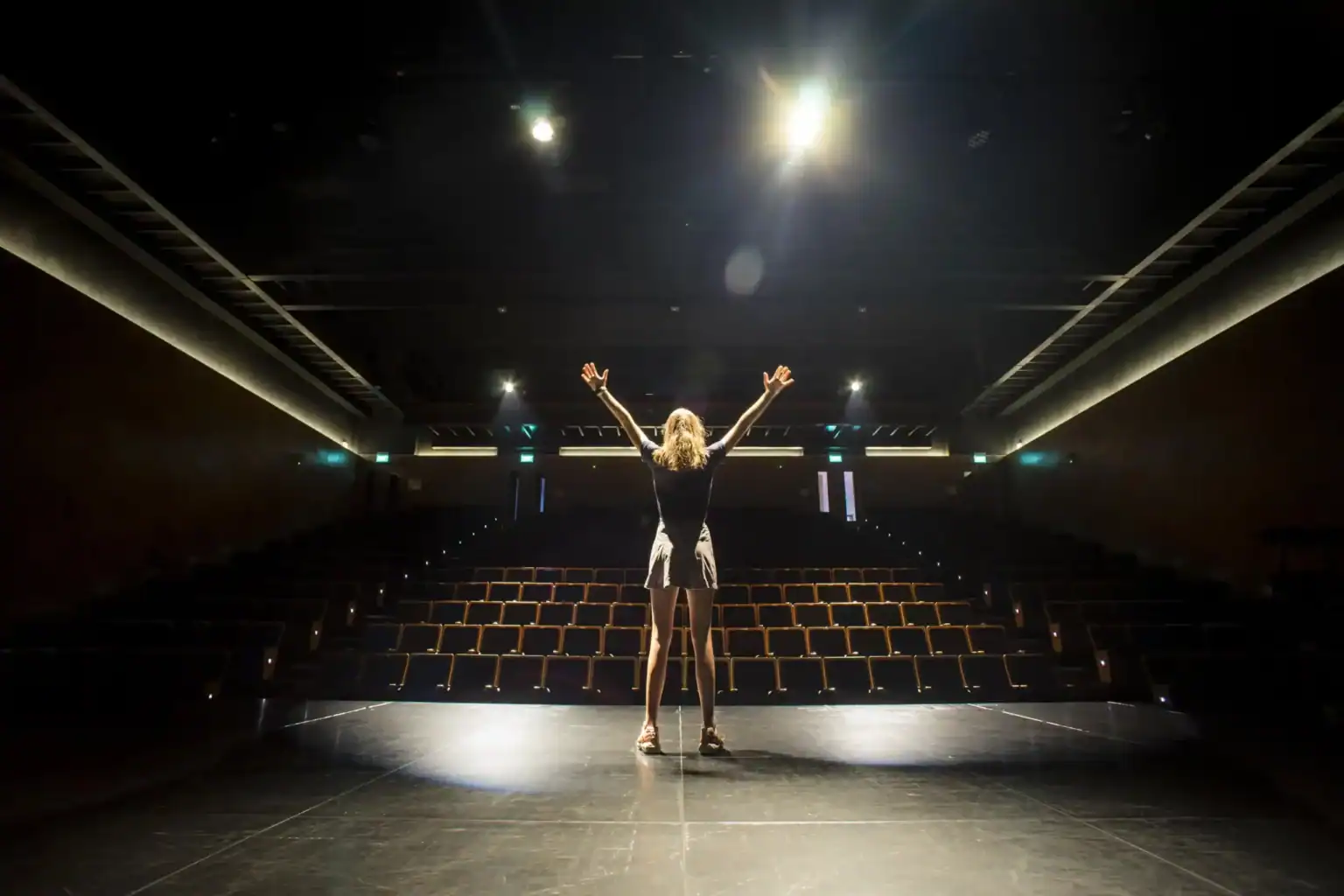 Open-minded student performing on stage in an auditorium, fostering creativity and confidence.