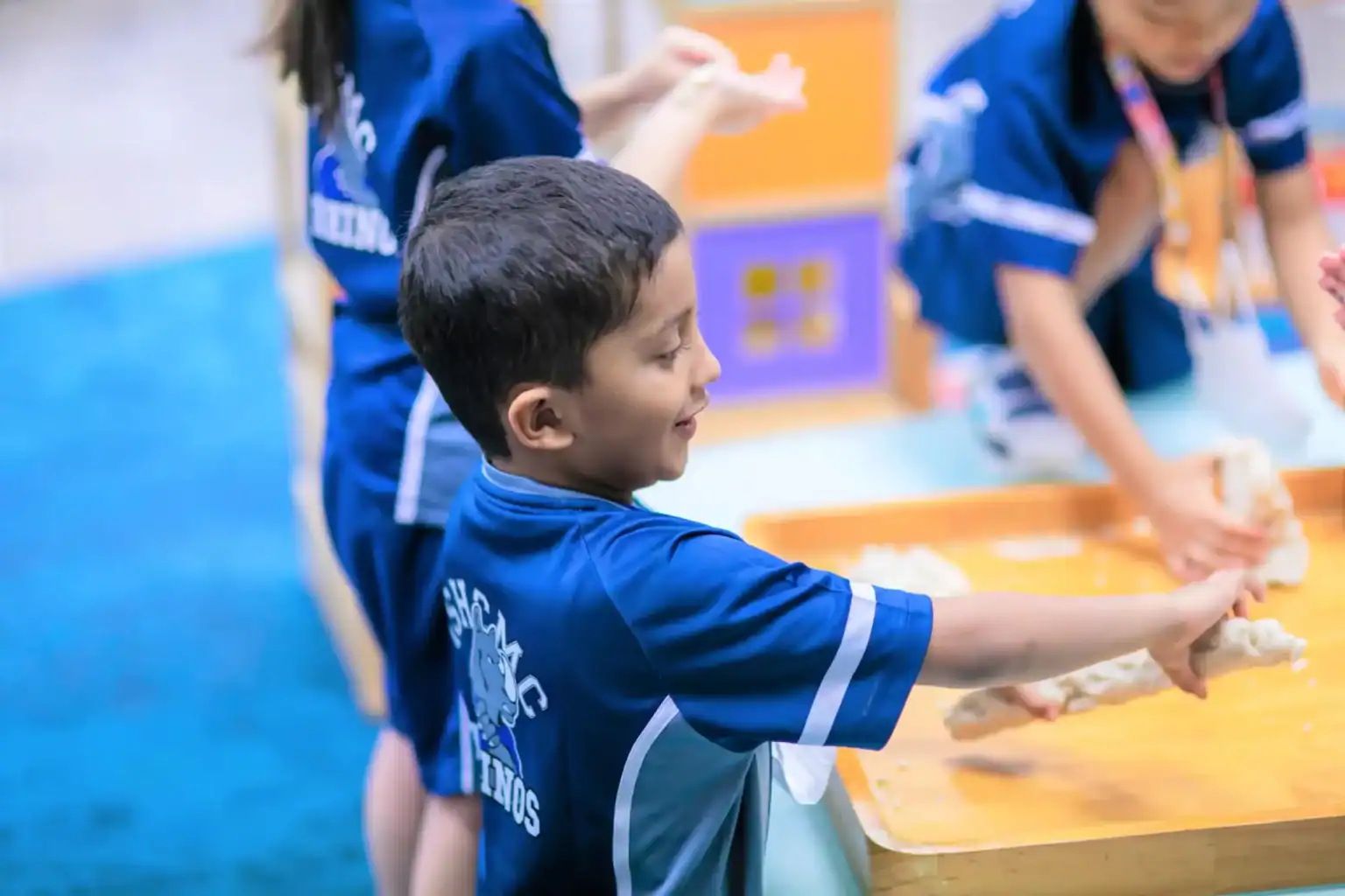 Happy young boy playing with dough in a school activity, children engaged in hands-on learning.