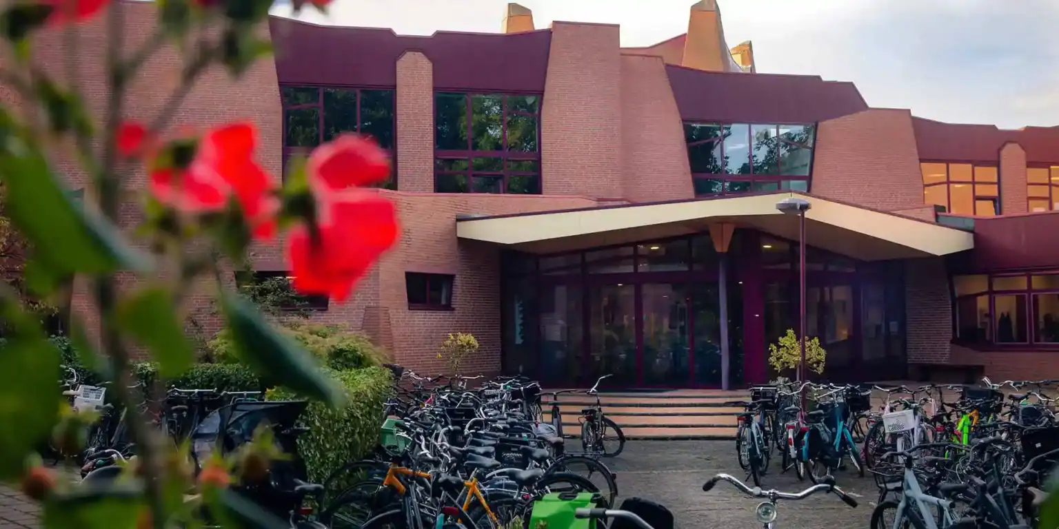 Nowoczesny kampus międzynarodowej szkoły z parkingiem dla rowerów, bujną zielenią i współczesną architekturą.