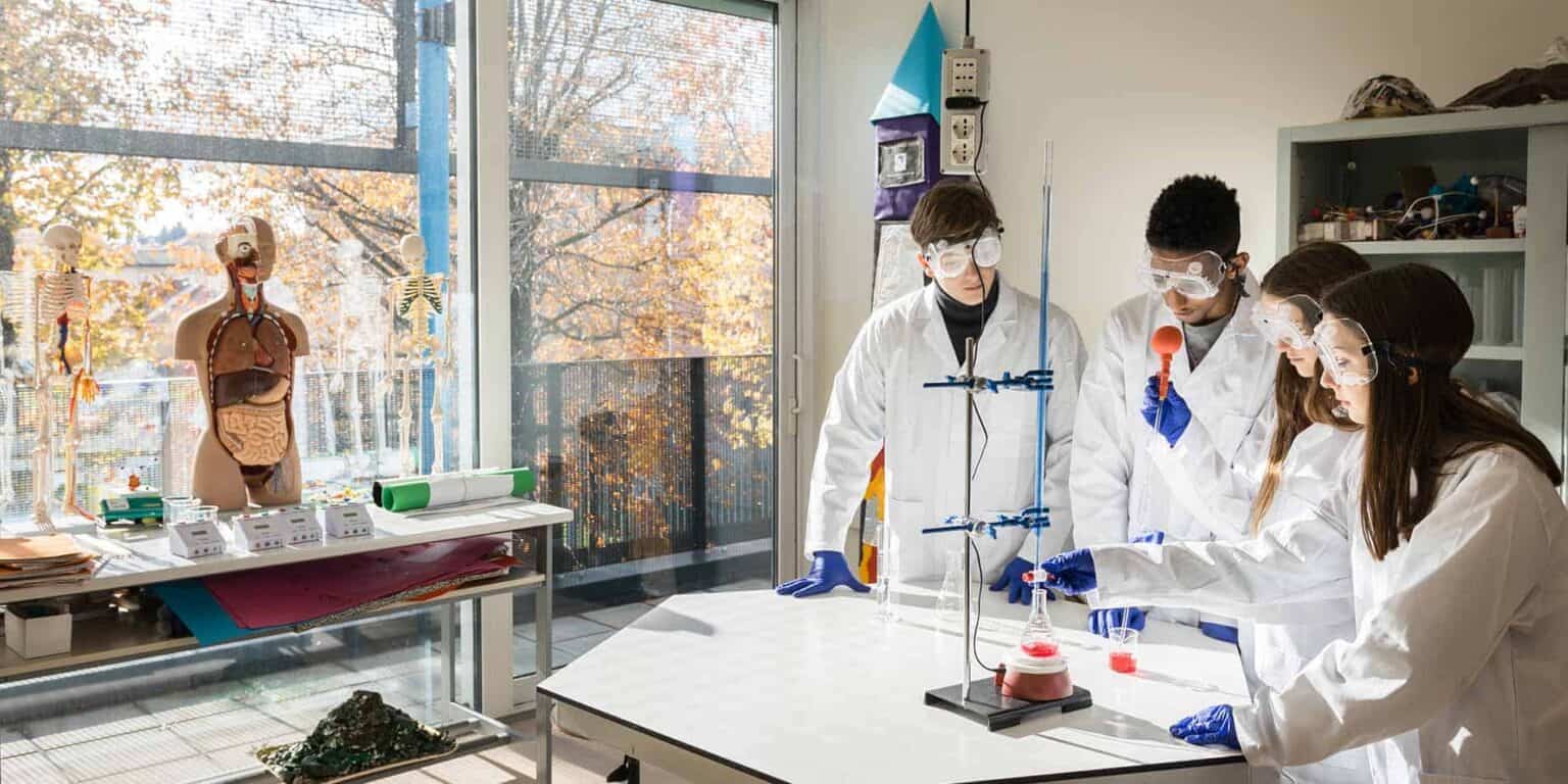 Students conducting science experiments in a modern school lab for international education.