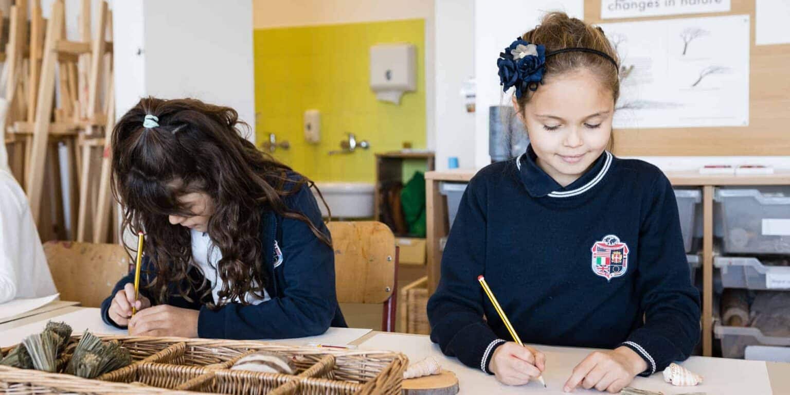 Colorful classroom with young girls engaging in learning activities, emphasizing international education and diverse school environments.