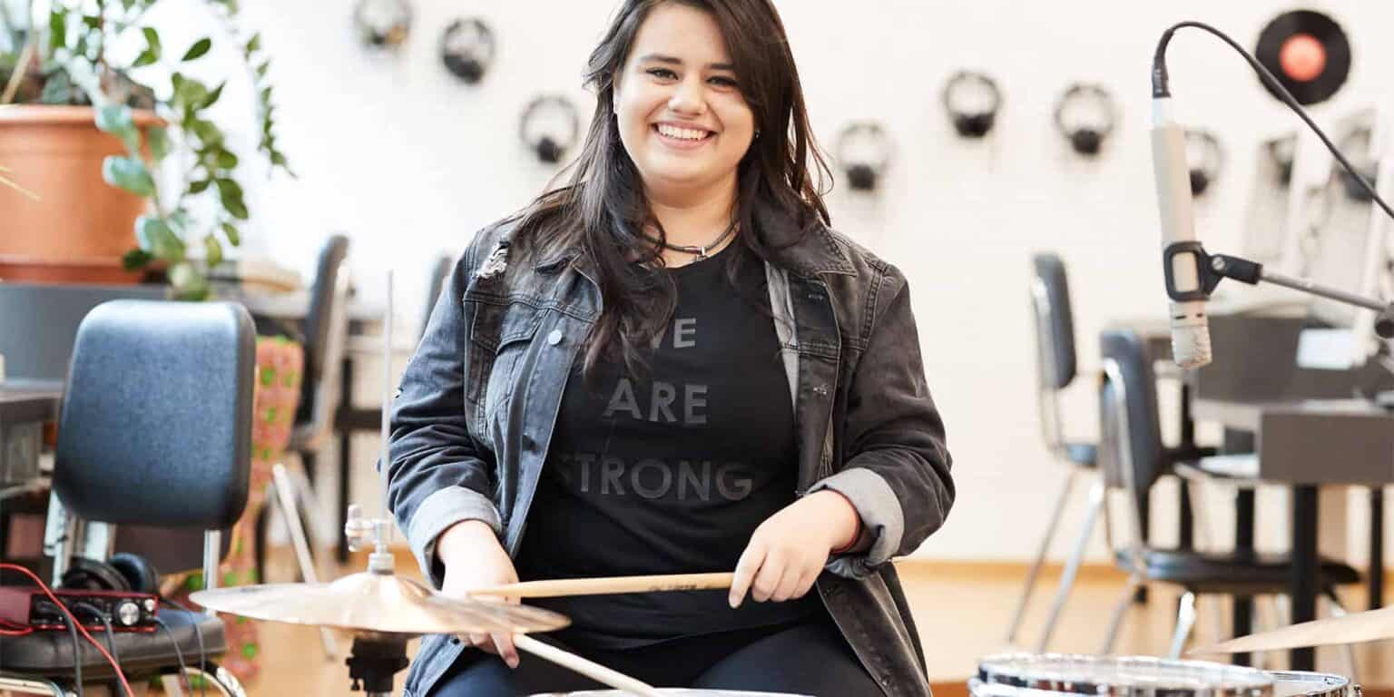 Music student playing drums in a classroom, fostering creativity and arts education at World Schools.