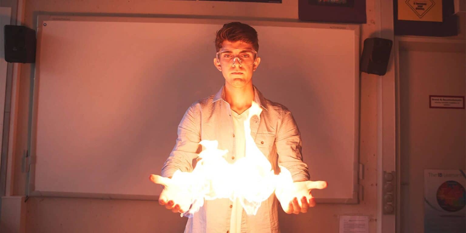 Vibrant science experiment in classroom with fire and student performing a chemistry demonstration for education.