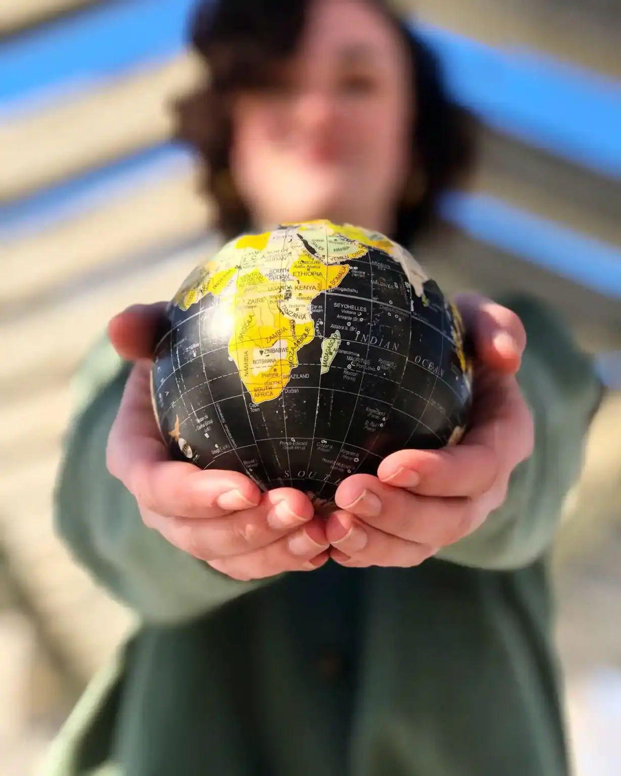Colorful globe focusing on Africa, held by an individual with blurred face, symbolizing global education and international schools.