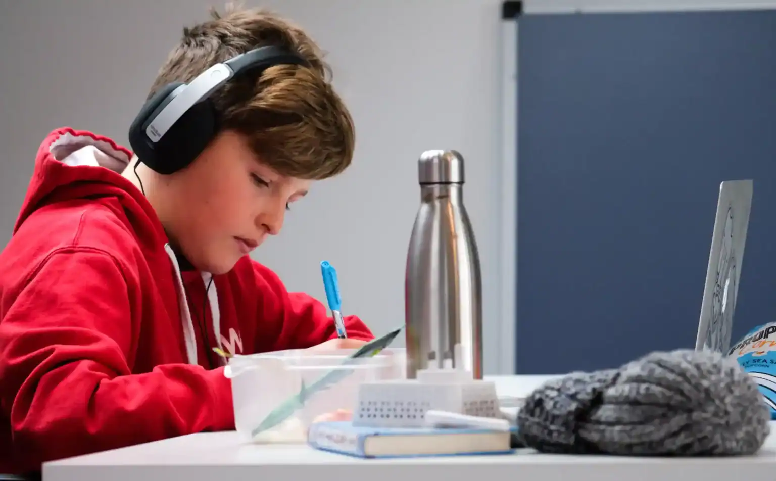 Young student focused on homework, studying in a school setting with headphones.