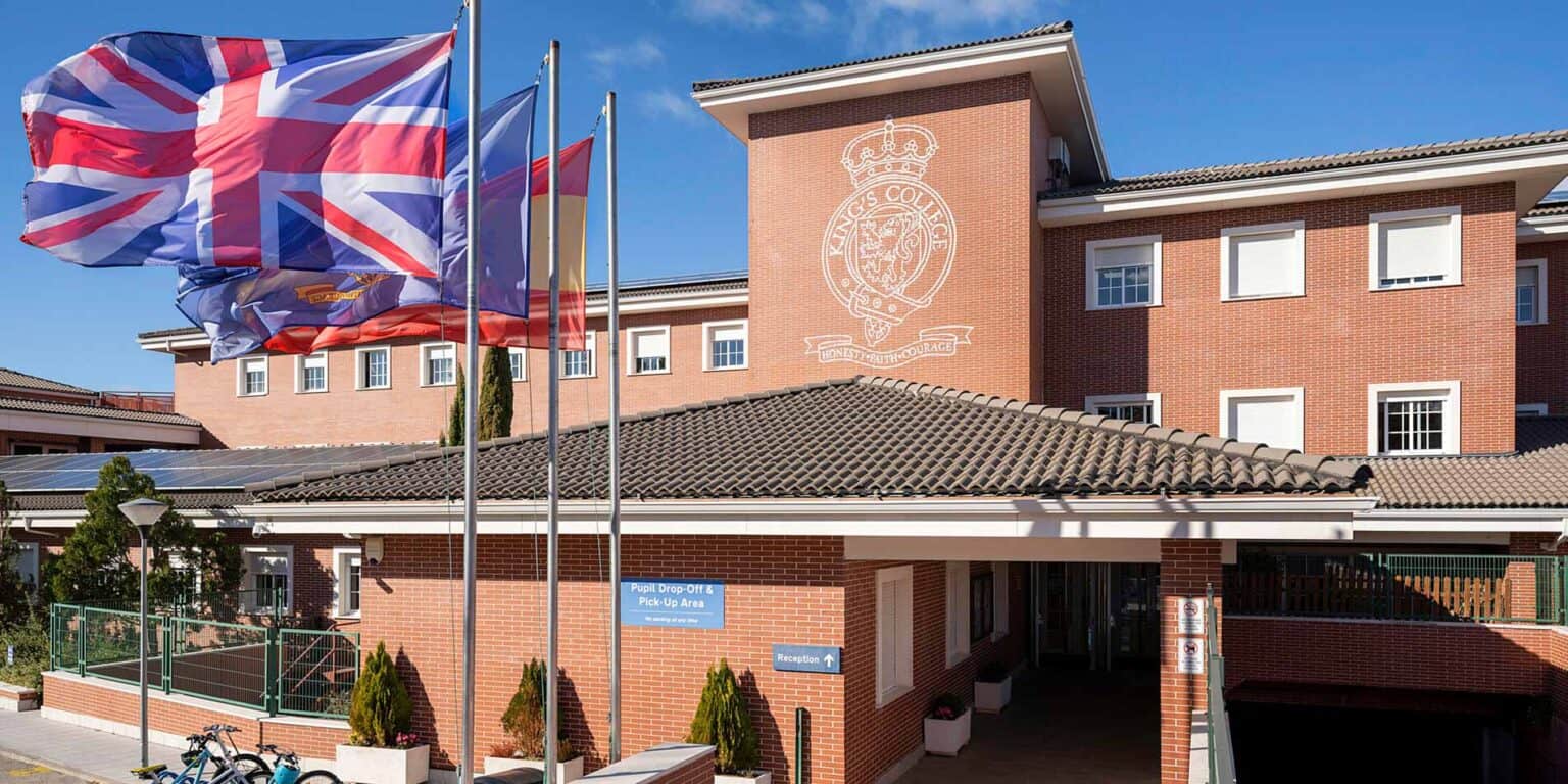 Bright red brick school building with flags and emblem, welcoming educational environment at World Schools site.