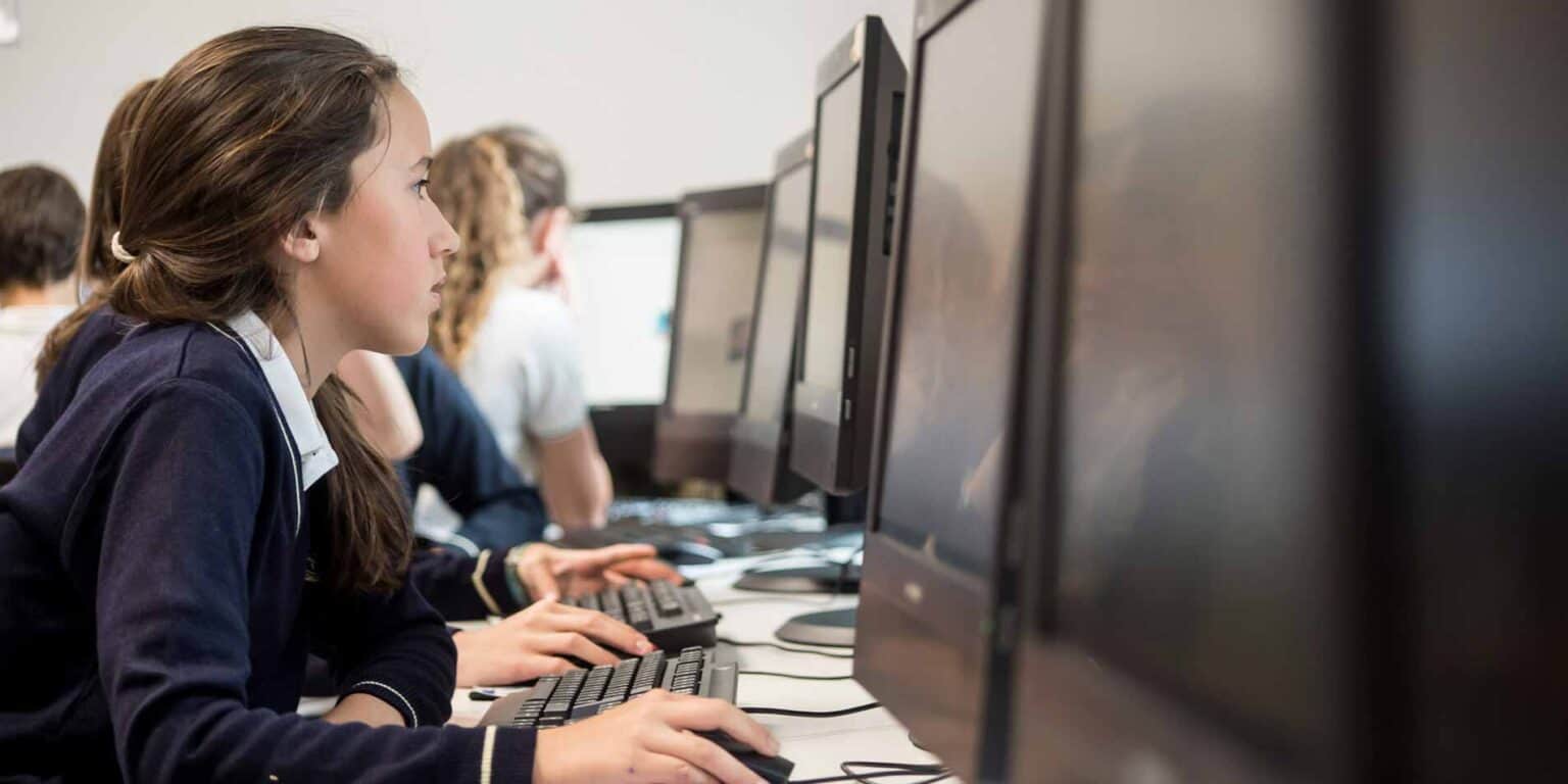 Focused girl using a computer in a modern classroom at a world school.
