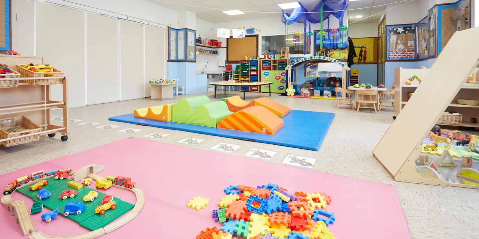 Bright colorful early childhood classroom with toys, slides, and play areas for young children.