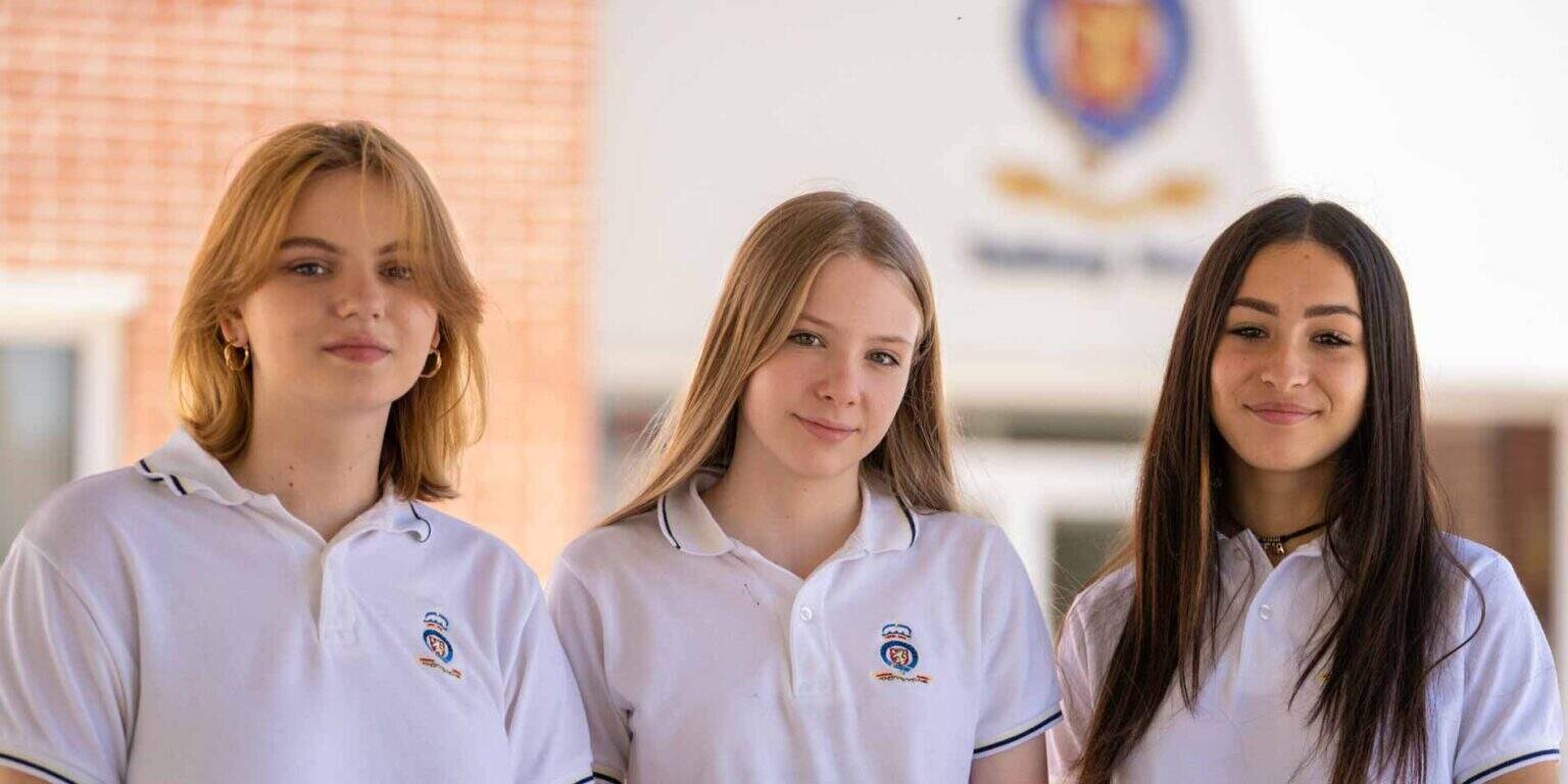 Bright young students in white uniforms standing outside a school building, representing World Schools' academic excellence and diverse student community.