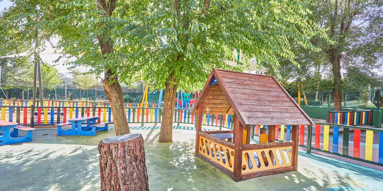 Colorful outdoor playground at a World Schools campus with trees and play structures for children.