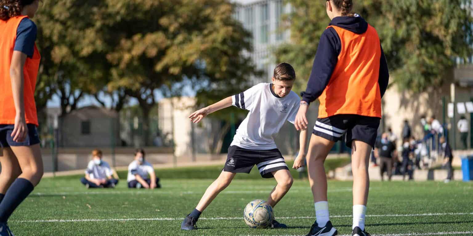 Young students playing soccer outdoors at a World Schools athletic event.