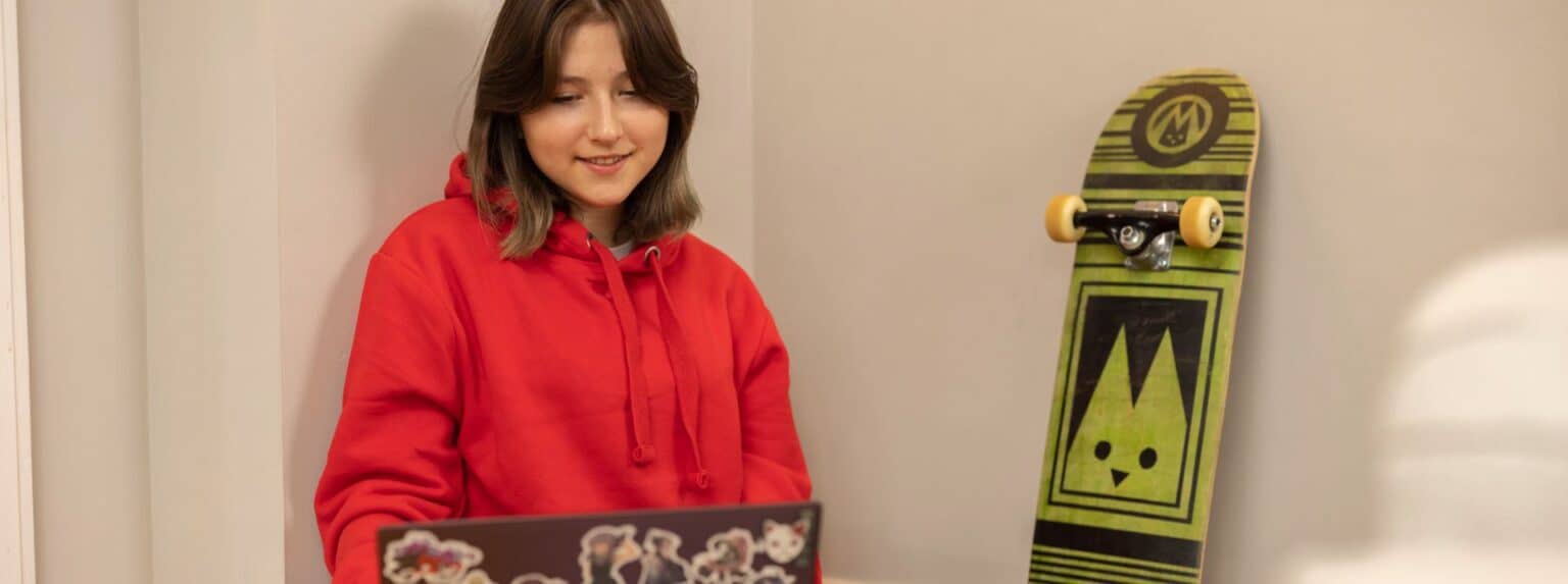Girl studying with a skateboard near wall at World Schools facility.