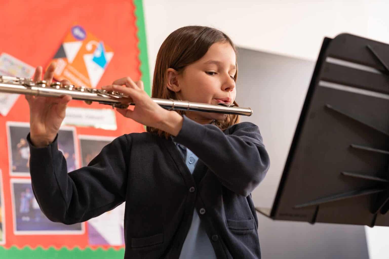Young girl playing flute in school classroom, learning music at World Schools.