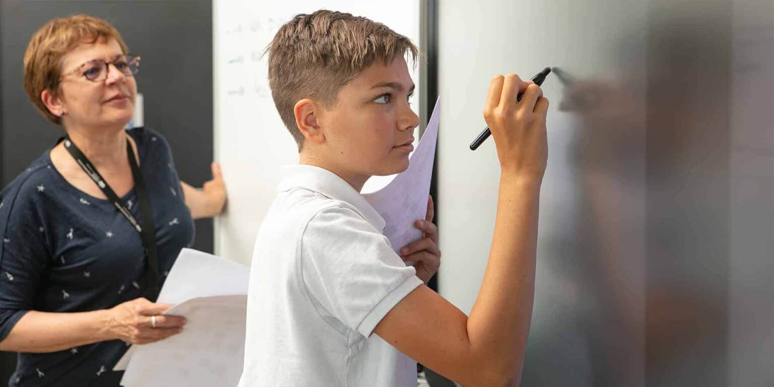 Bright student writing on smartboard during class at a world school.