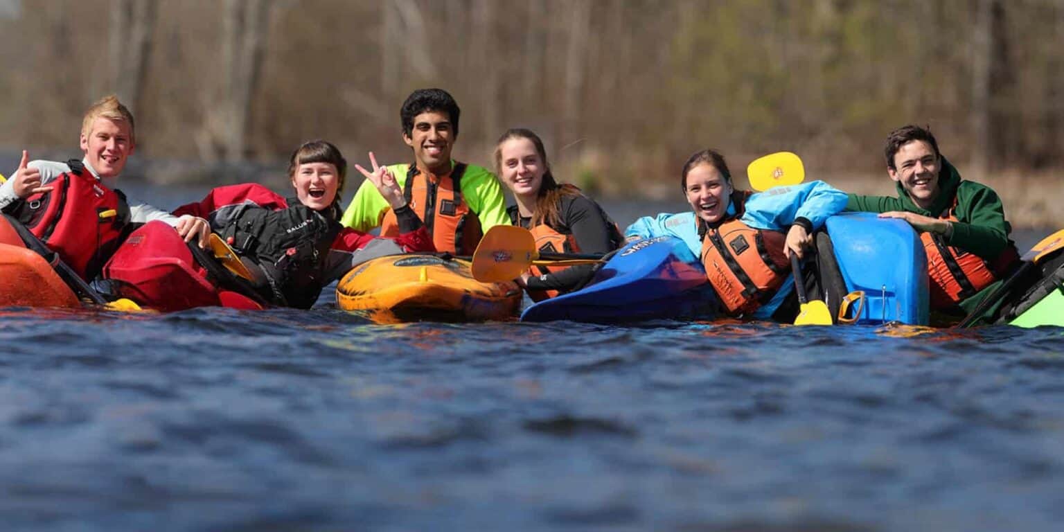 Adventurous students kayaking outdoors, enjoying teamwork and nature at a top international school.