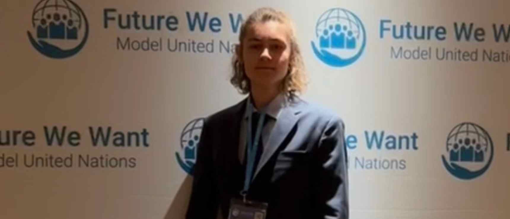 Young student standing in front of "Future We Want" United Nations event backdrop, promoting global education and leadership.
