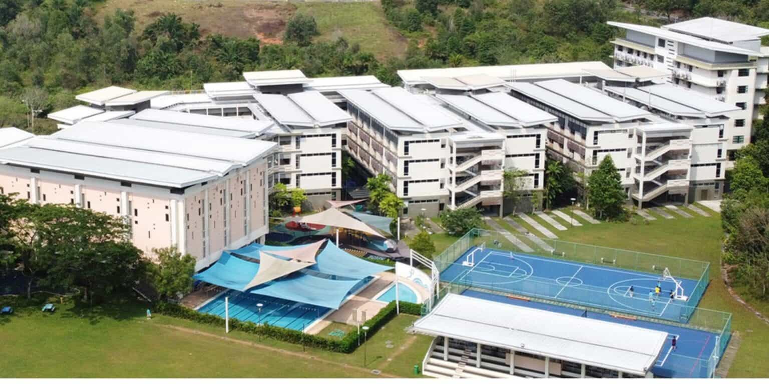 Modern international school campus with sports facilities, lush greenery, and student recreation areas.