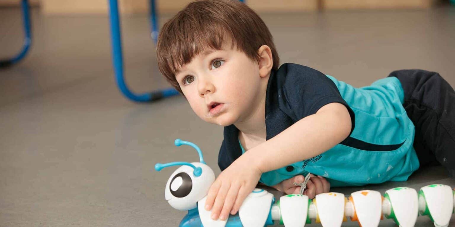 Child playing with educational robot in classroom, fun learning at World Schools for young students.