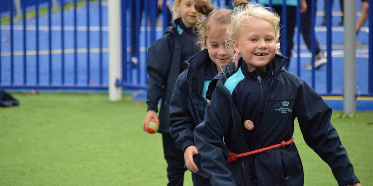 Children playing and smiling outdoors at a school sports field, emphasizing joy and active learning at World Schools.