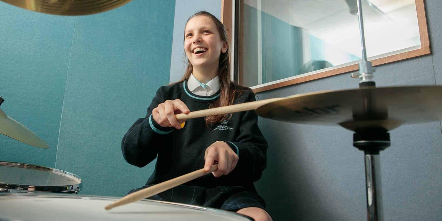 Energetic student playing drums in a music classroom at a world school for diverse education.