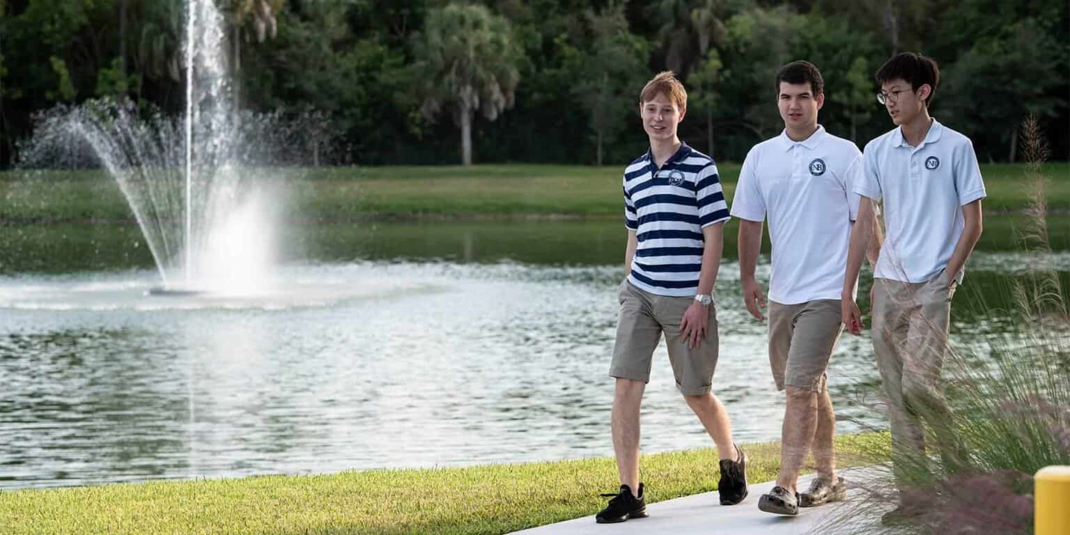 Students walking near a scenic pond at a prestigious international school environment.