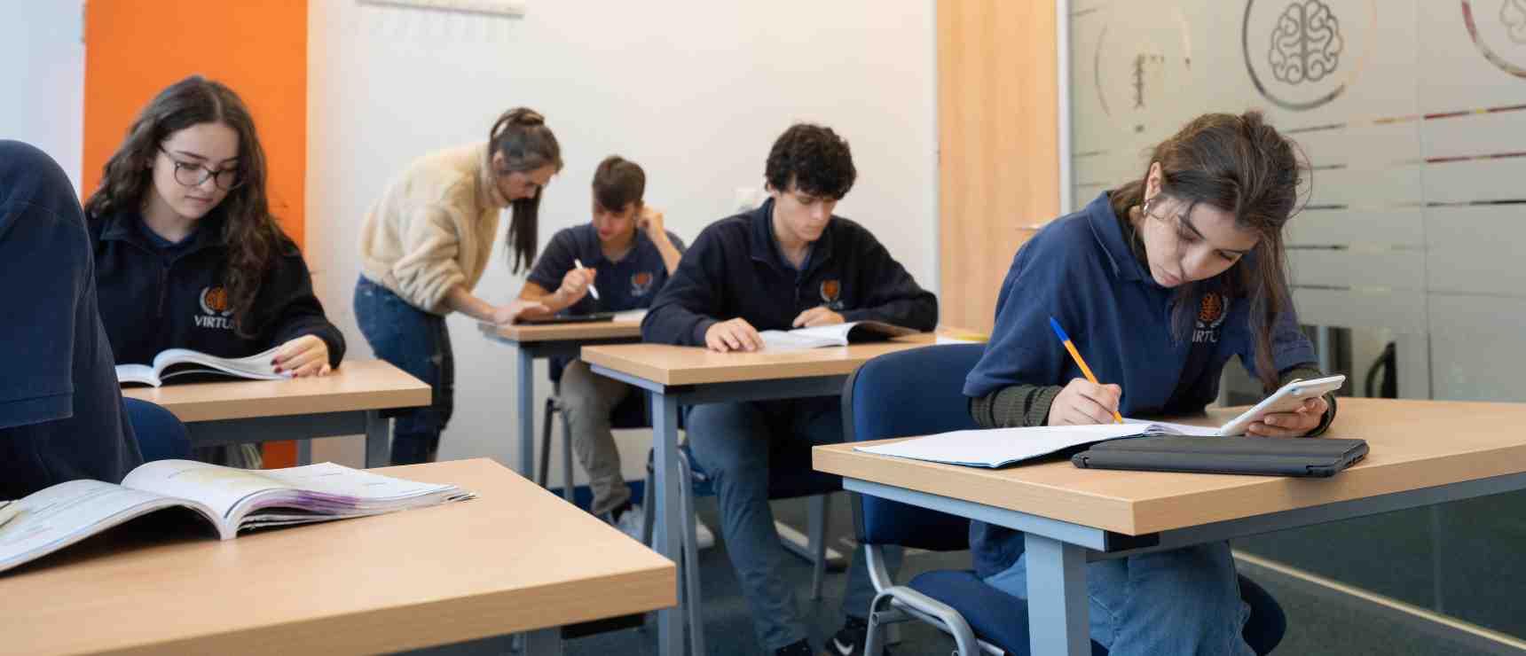 Students studying in a modern classroom with laptop and books, emphasizing international school education.