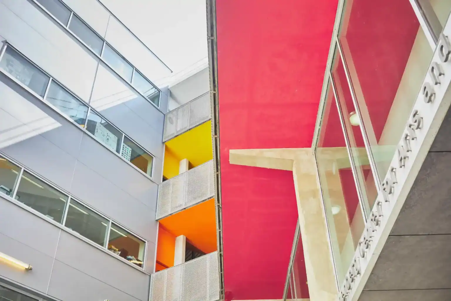Bright, modern school building with colorful balconies and vibrant red ceiling, exemplifying innovative educational environments.