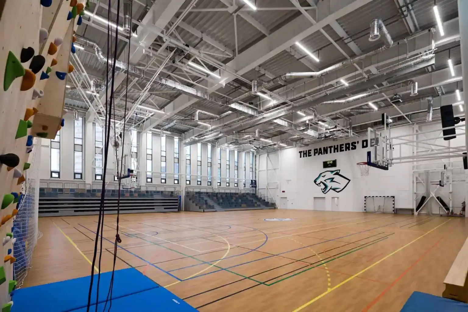 Bright indoor sports gymnasium with basketball court at The Panthers' Den, modern facilities for student athletics.
