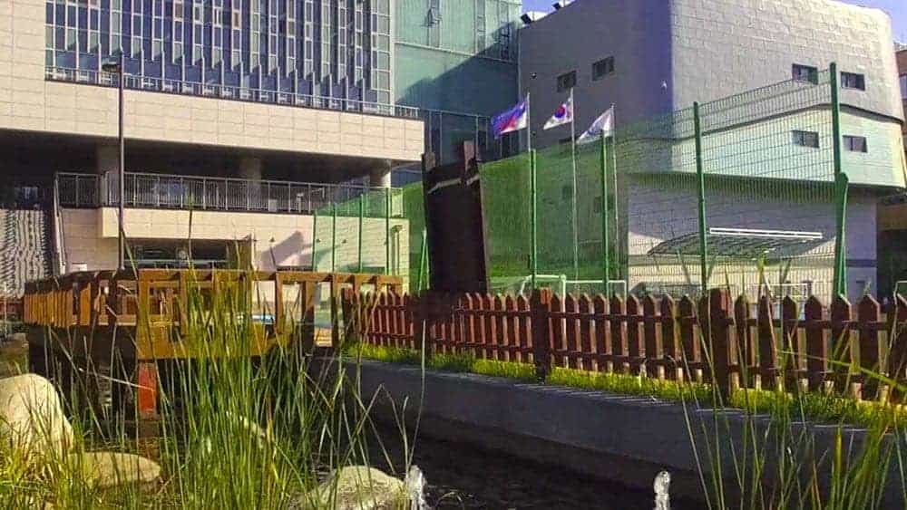Modern world school building with sports facilities and flagpoles, offering top international education.