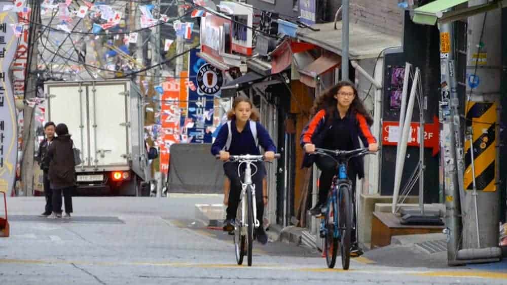 Modern urban street scene with students cycling, showcasing vibrant city life and active transportation.