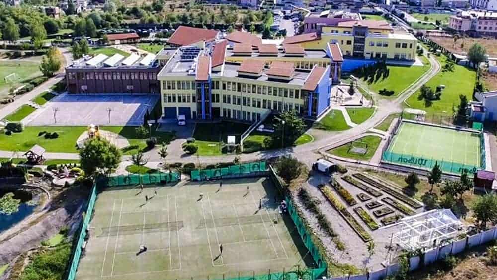Modern international school campus with sports facilities and lush green grounds for global education.