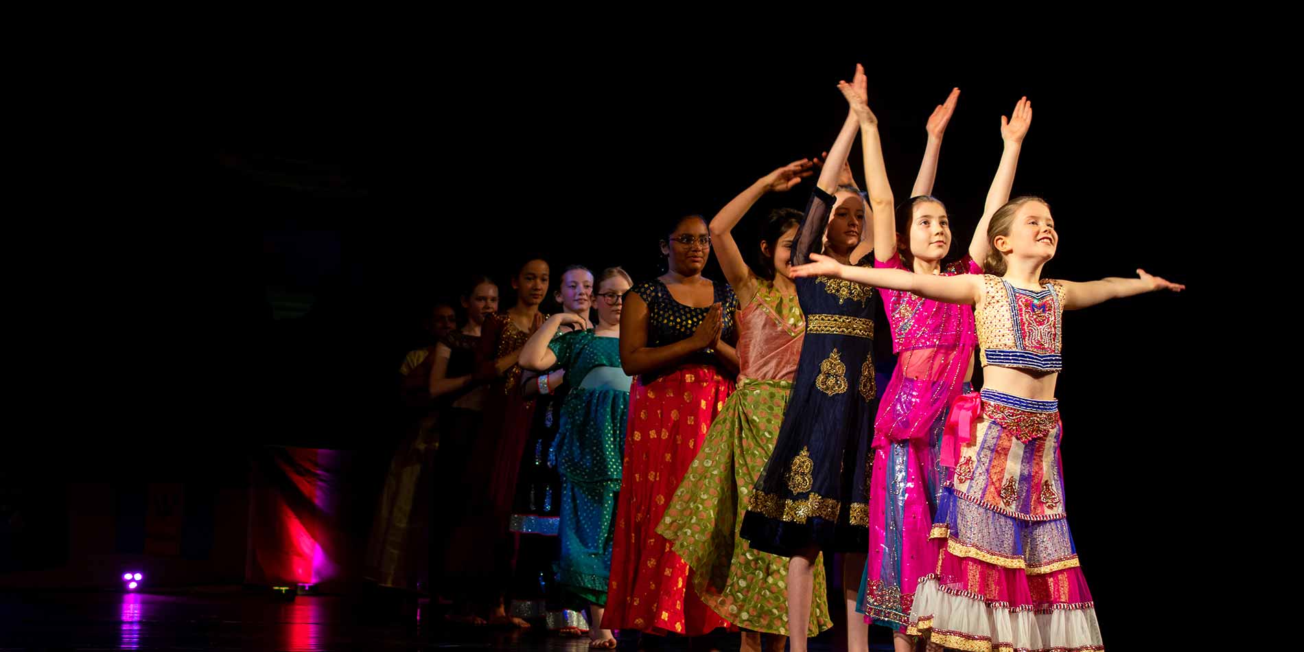 Colorful children performing traditional dance at a multicultural school event.