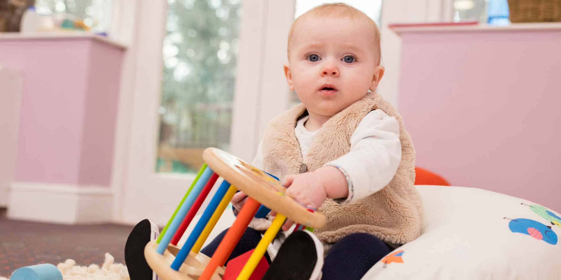 Baby playing with colorful educational toys in a bright, modern nursery.