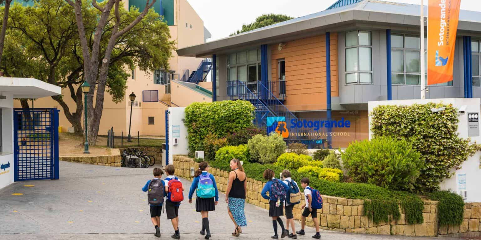 Sunny school entrance at Sotogrande International School with students and teacher.