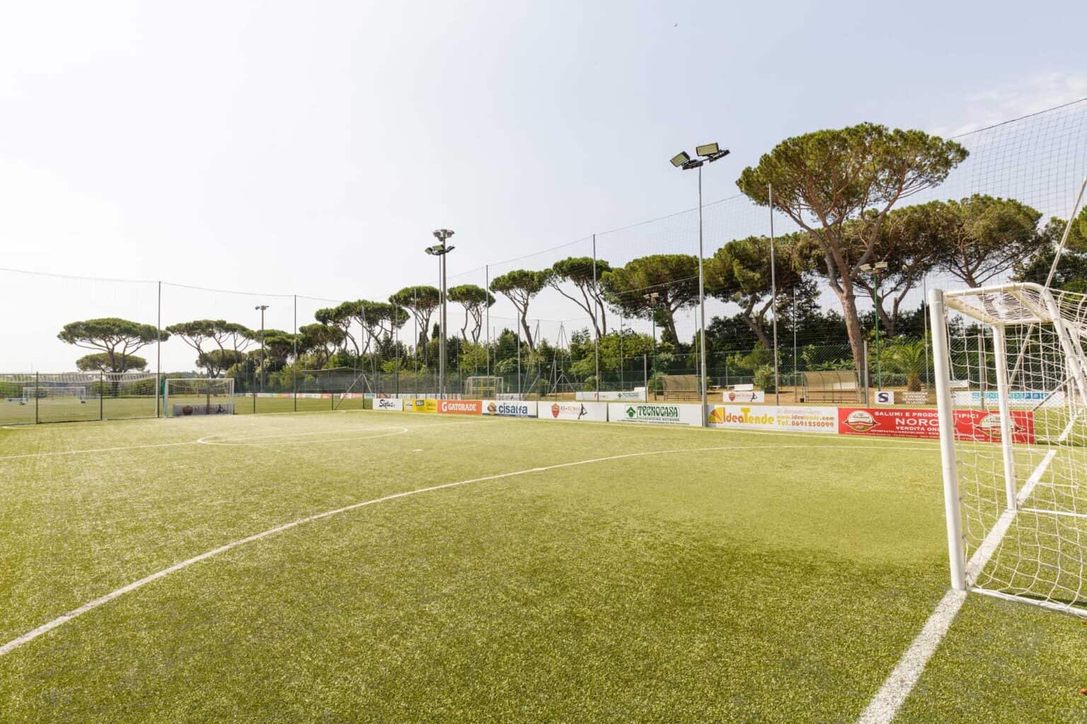 1. Campo da calcio presso le Scuole Mondiali con alberi circostanti e illuminazione luminosa.