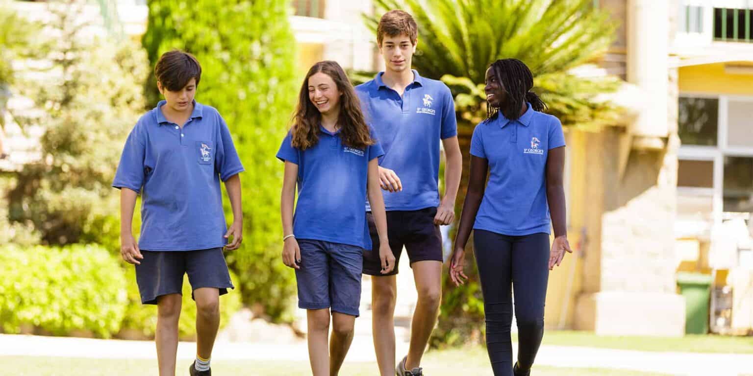 Studenti brillanti che camminano all'aperto in una prestigiosa scuola internazionale, mostrando studenti diversi e impegnati.