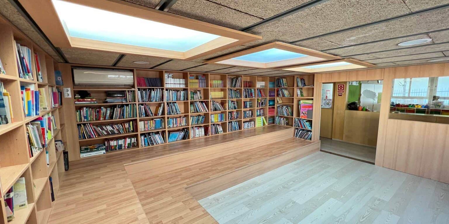 Öğrencilerin öğrenmesi ve okuması için ahşap kitap rafları ve tavan pencereleri olan renkli okul kütüphanesi.