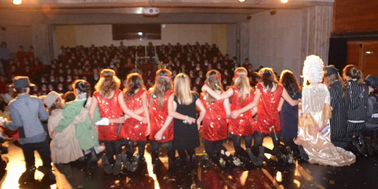 Kültürel bir etkinlik sırasında sahnede kostümlü öğrencilerle zarif okul performansı.