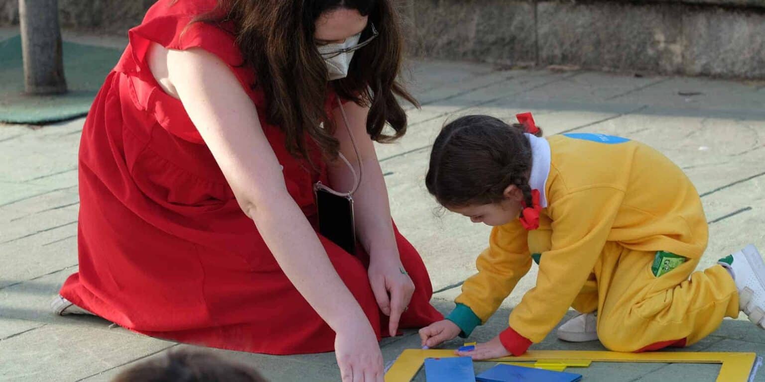 Parlak giyimli öğretmen ve öğrenci bir dünya okulu etkinliğinde açık hava eğitim faaliyetine katılıyor.