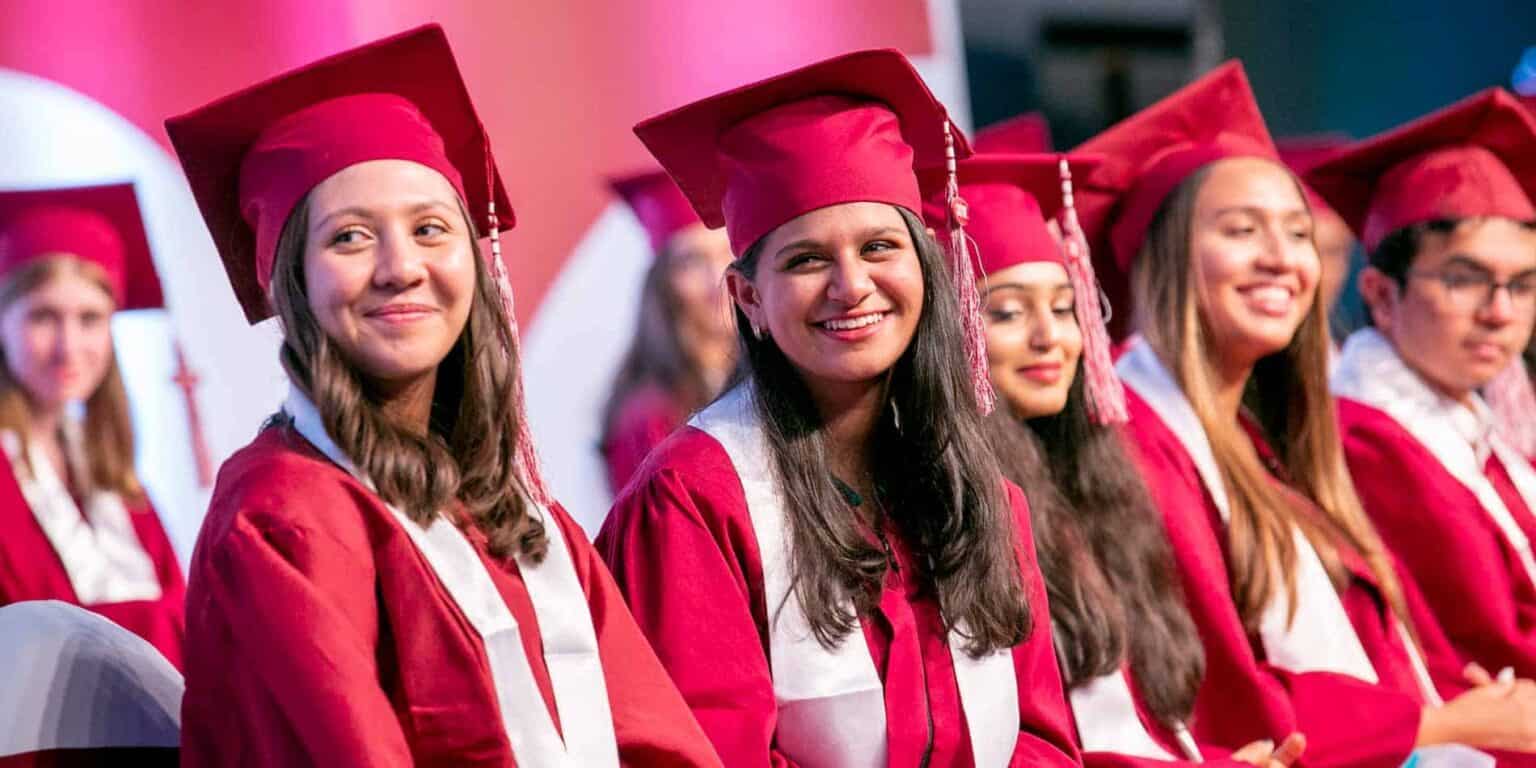 Graduates in red caps and gowns celebrating at a school graduation ceremony.