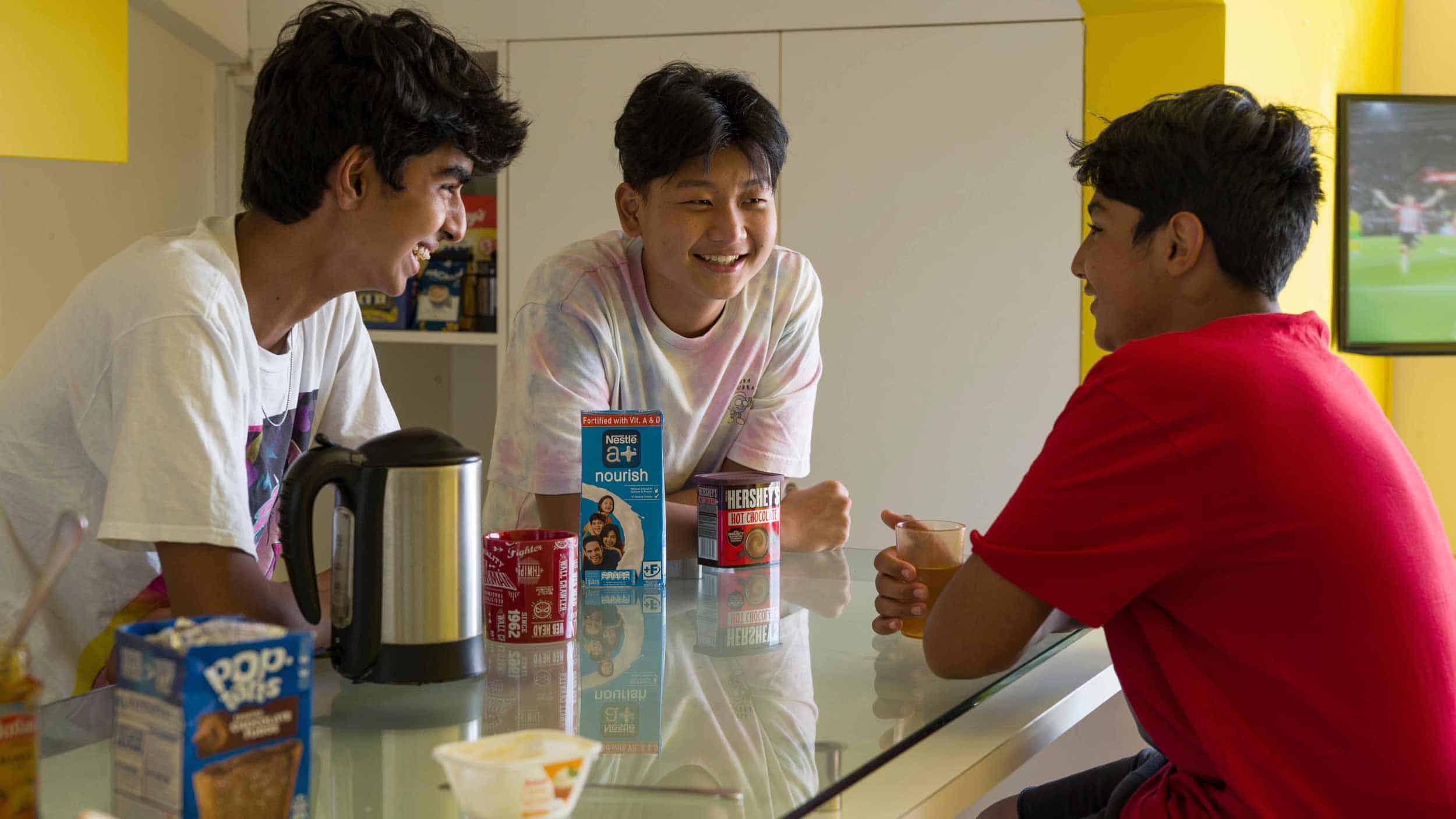 Cheerful students chatting during breakfast at a diverse international school classroom.