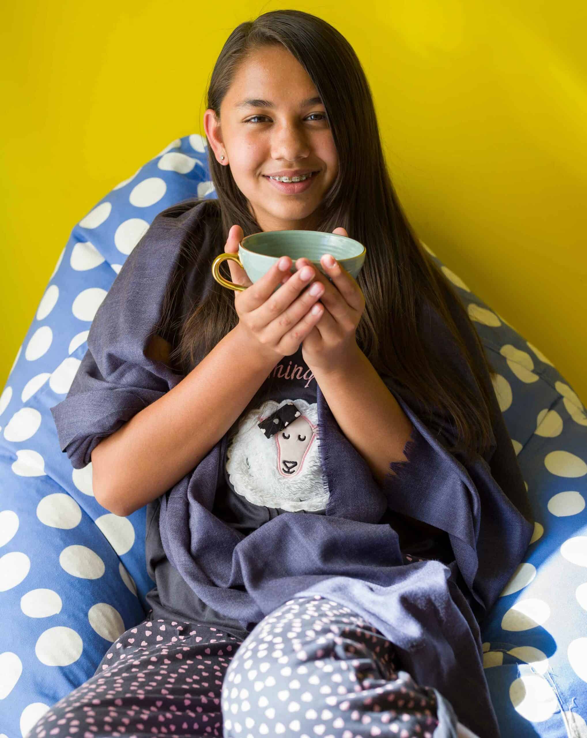Bright young girl enjoying tea time at home, promoting healthy lifestyle and relaxation.