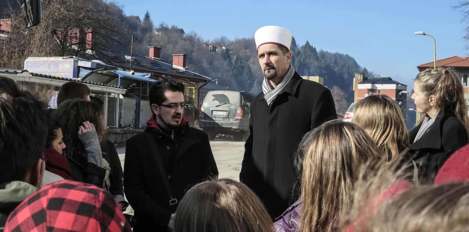 Outdoor group of students listening to a chef in a chef's hat on a school trip or event.
